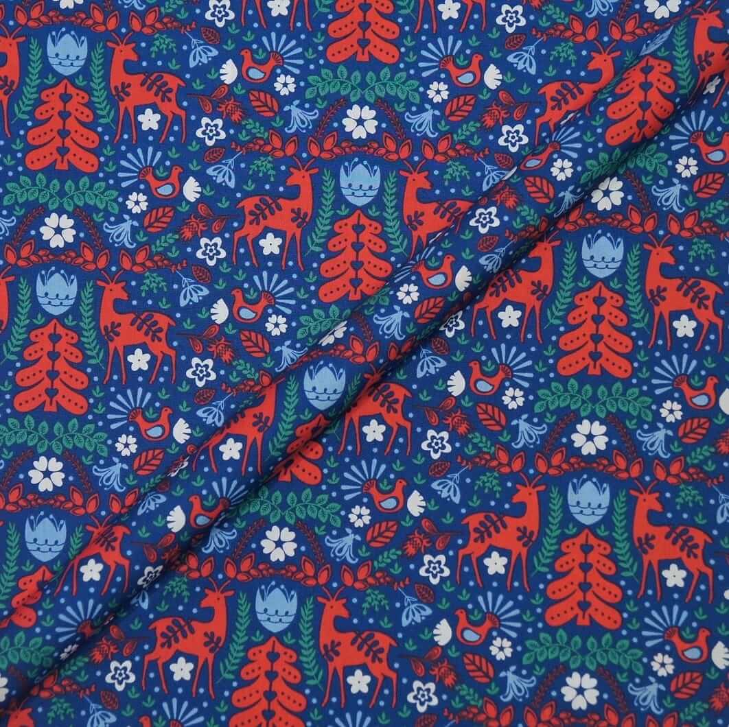 Patterned fabric with red deer, blue trees, and green leaves on a blue background